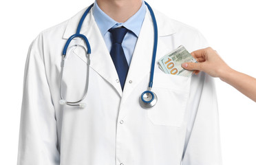 Patient putting bribe into doctor's pocket on white background, closeup. Corruption in medicine