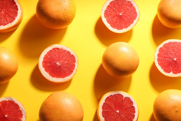 Cut and whole ripe grapefruits on yellow background, flat lay