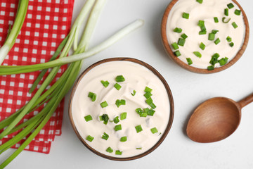 Fresh sour cream with onion on white table, flat lay