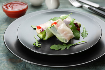Delicious rolls wrapped in rice paper on light blue wooden table, closeup