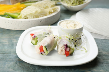 Delicious rolls wrapped in rice paper served on light blue wooden table