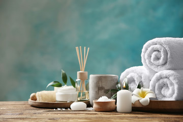 Beautiful spa composition with towels on wooden table against light blue background