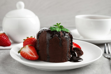 Delicious warm chocolate lava cake with mint and strawberries on table