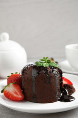 Delicious warm chocolate lava cake with mint and strawberries on table. Space for text