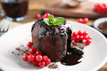 Delicious warm chocolate lava cake with mint and berries on plate, closeup