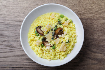 Delicious risotto with cheese and mushrooms on wooden table, top view