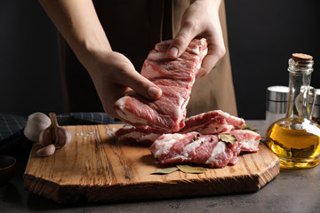 Man holding raw ribs at grey table, closeup