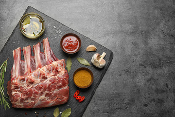 Raw ribs with herbs and spices on grey table, flat lay