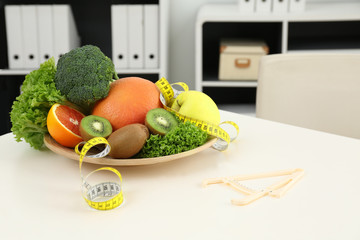 Nutritionist's workplace with fruits, vegetables, measuring tape and body fat caliper on table