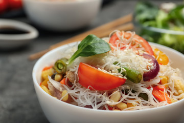 Tasty cooked rice noodles with vegetables on table, closeup