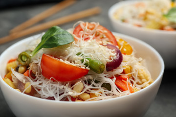 Tasty cooked rice noodles with vegetables on table, closeup