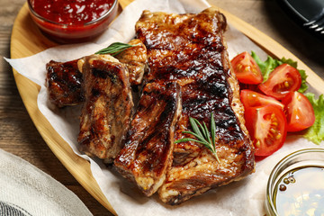 Delicious grilled ribs served on wooden table, closeup