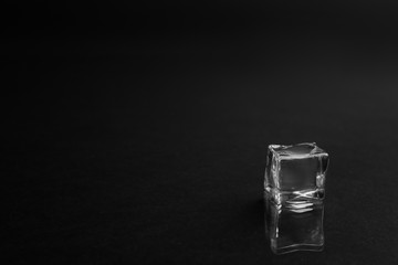 Crystal clear ice cube on black background. Space for text