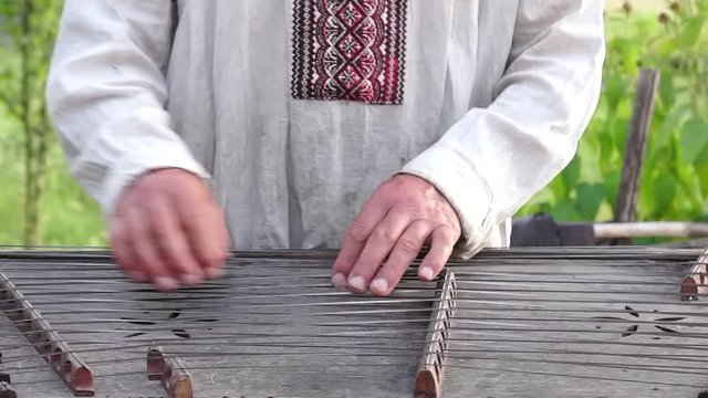 Man playing the old wooden craft dulcimer cymbalo folk musical instrument slow motion close up