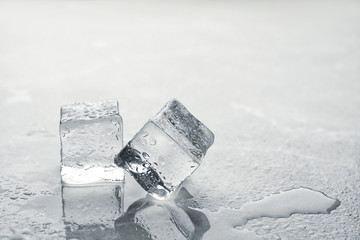 Crystal clear ice cubes with water drops on metal surface. Space for text
