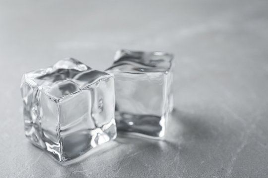 Crystal clear ice cubes on grey table, closeup