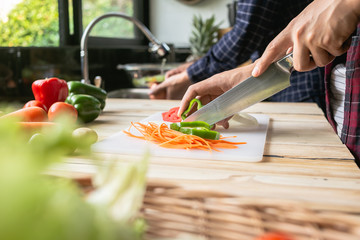 Close-up man cooking and slicing fresh vegetables on a rustic kitchen worktop, healthy eating concept, flat lay