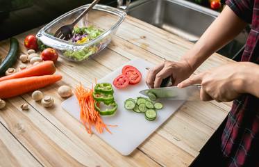 Close-up man cooking and slicing fresh vegetables on a rustic kitchen worktop, healthy eating concept, flat lay
