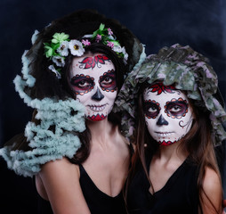 Mom and daughter with a sugar skull make-up on a dark background
