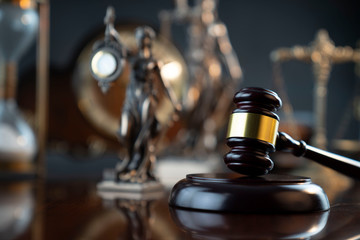 Law and justice theme. Judge’s gavel, Themis  statue, scale, hourglass and old clock on the shining wooden brown table and the gray background.