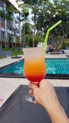 Bright cocktail in a hand on the background of the pool. Thailand. Samui