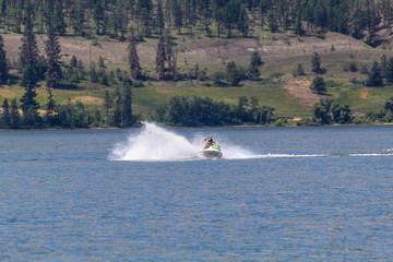  couple on speed boats jet ski having fun during water jet-ski jetski fast riding on water lake in Canada Okanagan Kelowna summer 