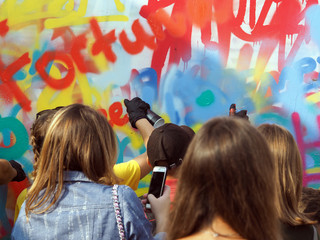 young people draw graffiti on the wall of the building