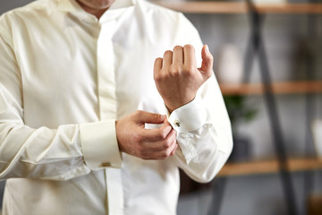 Obraz premium businessman dresses white shirt, male hands closeup,groom getting ready in the morning before wedding ceremony
