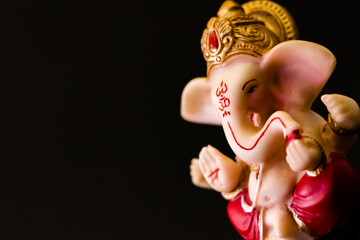 dutch shot close up of ganesha statue on black background with concept. hinduism and religious...