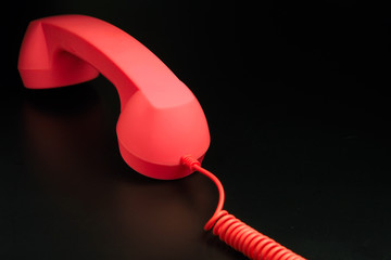red telephone receiver on black background