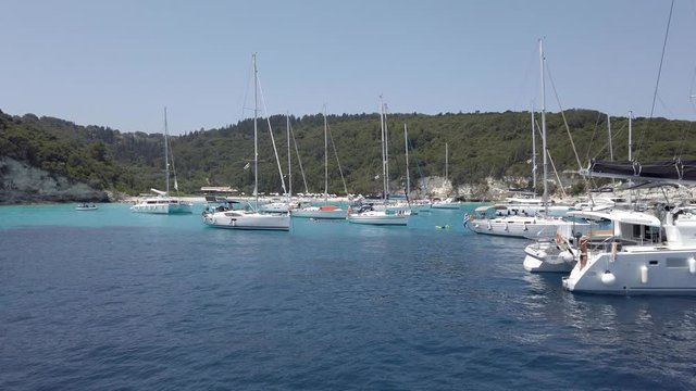 Tropical paradise turquoise beach of Voutoumi with sail boats docked in island of Antipaxos, Ionian, Greece