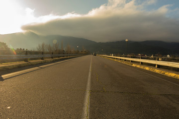 Puente de carretera con coche y niebla en el fondo