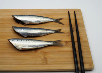 Lomos de sardinas sobre una tabla de bambú y palillos