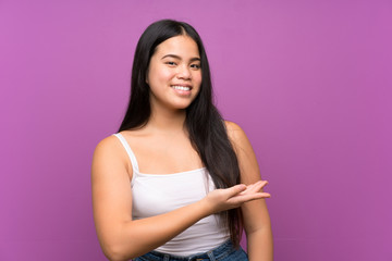Young teenager Asian girl over isolated purple background extending hands to the side for inviting to come