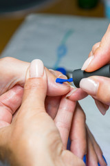 Beautiful manicure process. Nail polish being applied to hand, polish is a blue color. closeup. vertical photo