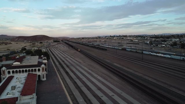 Static aerial at dusk over historic Amtrack Barstow Station with passing coal frieght train