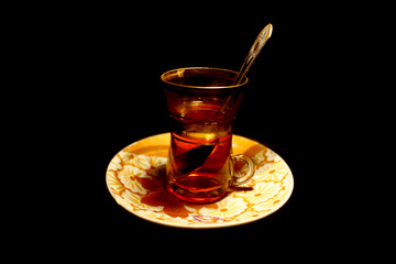 Golden turkish cup of tea with spoon isolated on black
