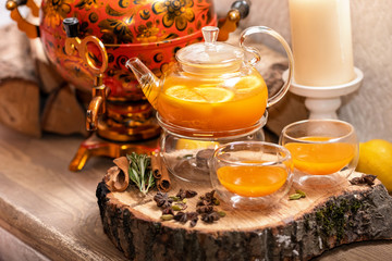 Sea Buckthorn tea candle basking in Russian restaurant. Vitaminic healthy sea buckthorn tea with cinnamon, lemon, rosemary, honey on wooden background.
