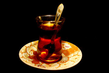 Simple turkish cup of tea with spoon isolated on black