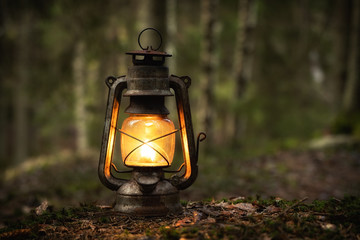 Vintage old lantern lighting in the dark forest. Travel camping concept. Burning lantern on a moss at forest in the night. - 317914468