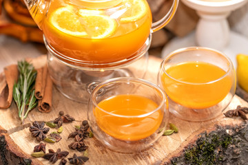 Sea Buckthorn tea candle basking in Russian restaurant. Vitaminic healthy sea buckthorn tea with cinnamon, lemon, rosemary, honey on wooden background.