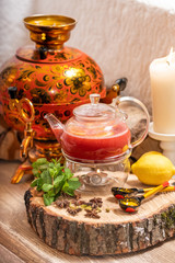 Hot fruit red berry tea with steam in the teapot, a cup of tea, with mint, berries, lemon slices on on wooden background. Food and drink, still life health care.