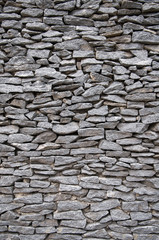 Full frame vertical close-up of flat gray stones stacked tightly in a wall