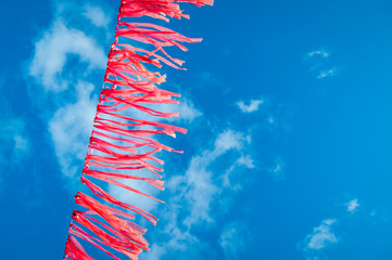 String of bright pink streamers flutters in the wind against vibrant blue sky