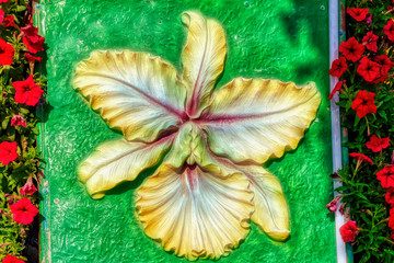 Plastic flower decoration surrounded by real flowers.