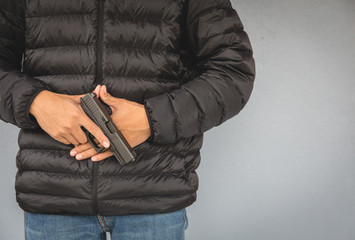 A man in a black coat with a short gun - 317917060