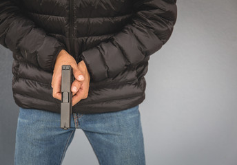 A man in a black coat with a short gun - 317917070