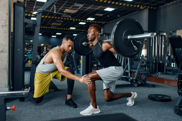 Obraz na płótnie Canvas Muscular sportsman and trainer on training in gym