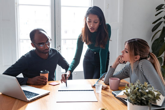 Pretty young entrepreneur woman explaining a project to his colleagues on coworking place.