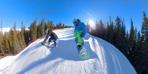 SELFIE: Two snowboarders riding down the fun park catch air and do tricks.